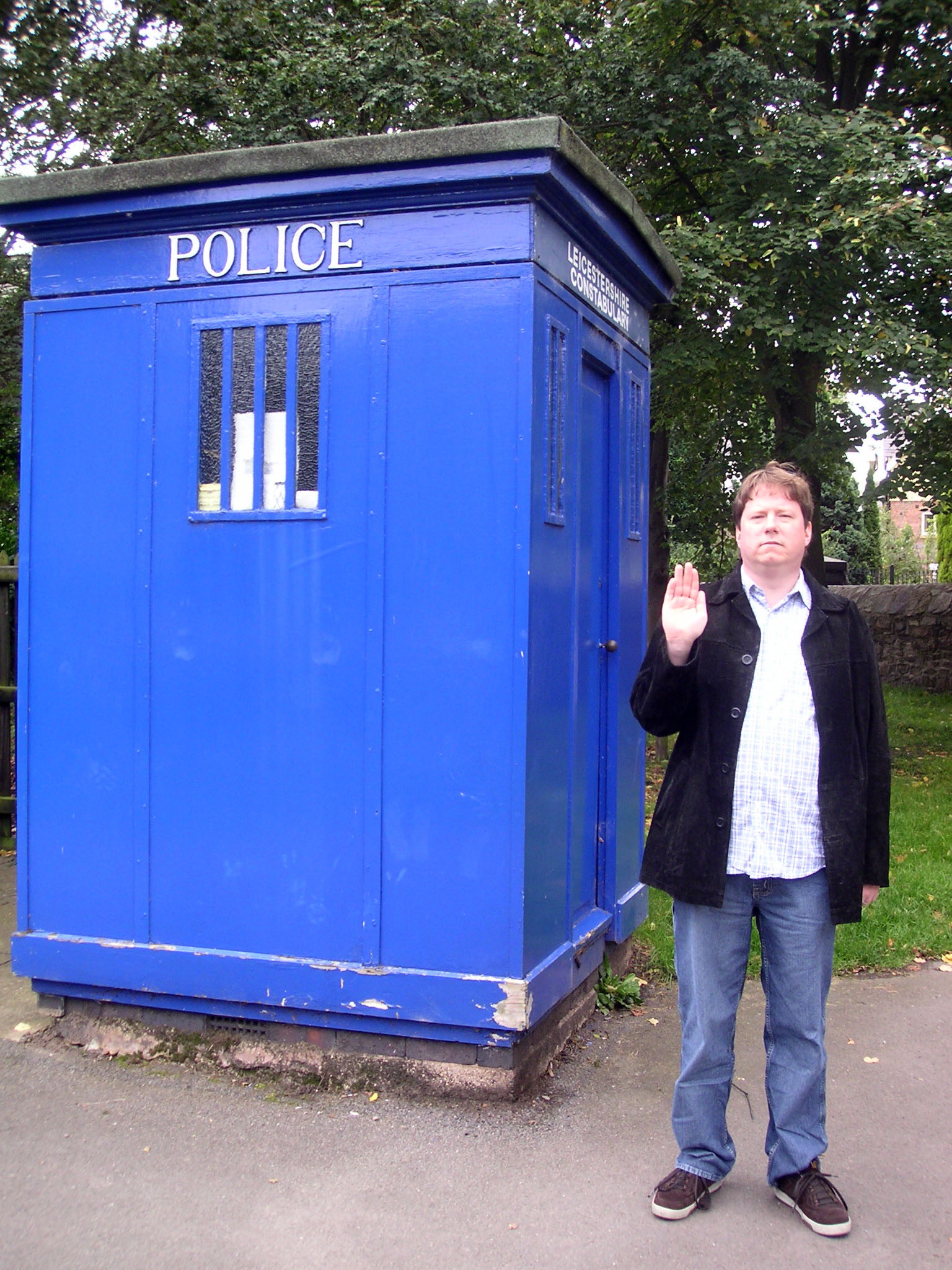 a person standing next to a blue portable toilet