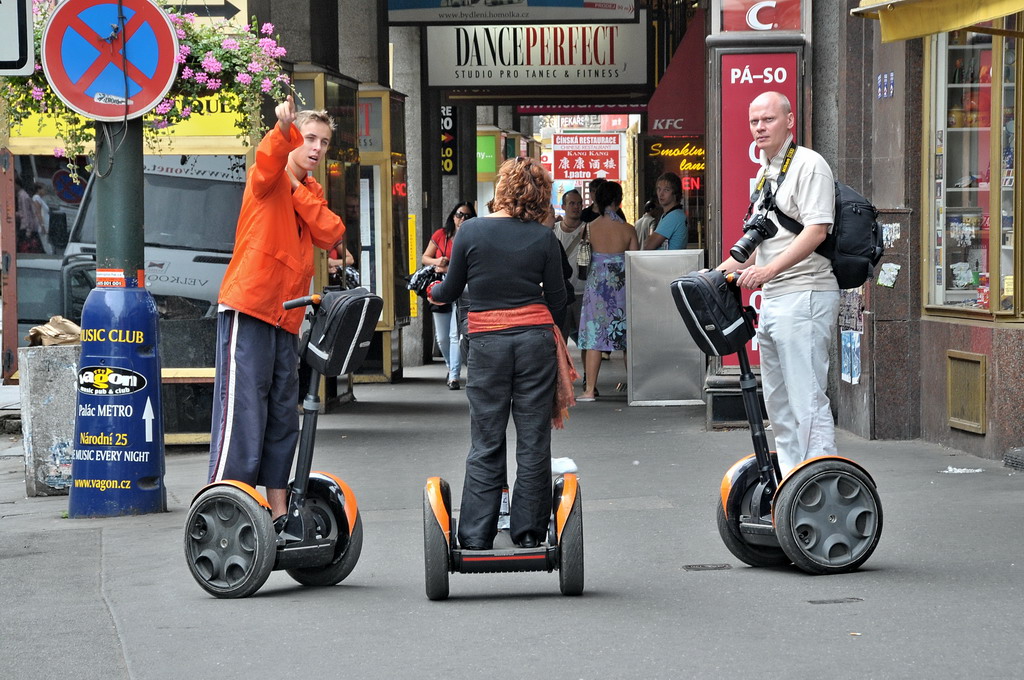 the two people on the street are riding electric scooters