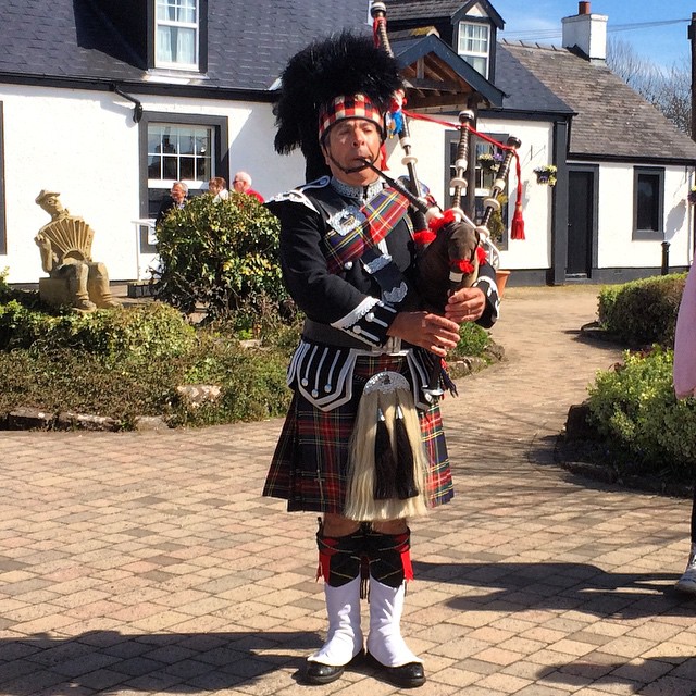 a person in a kilt playing bagpipes in front of a house