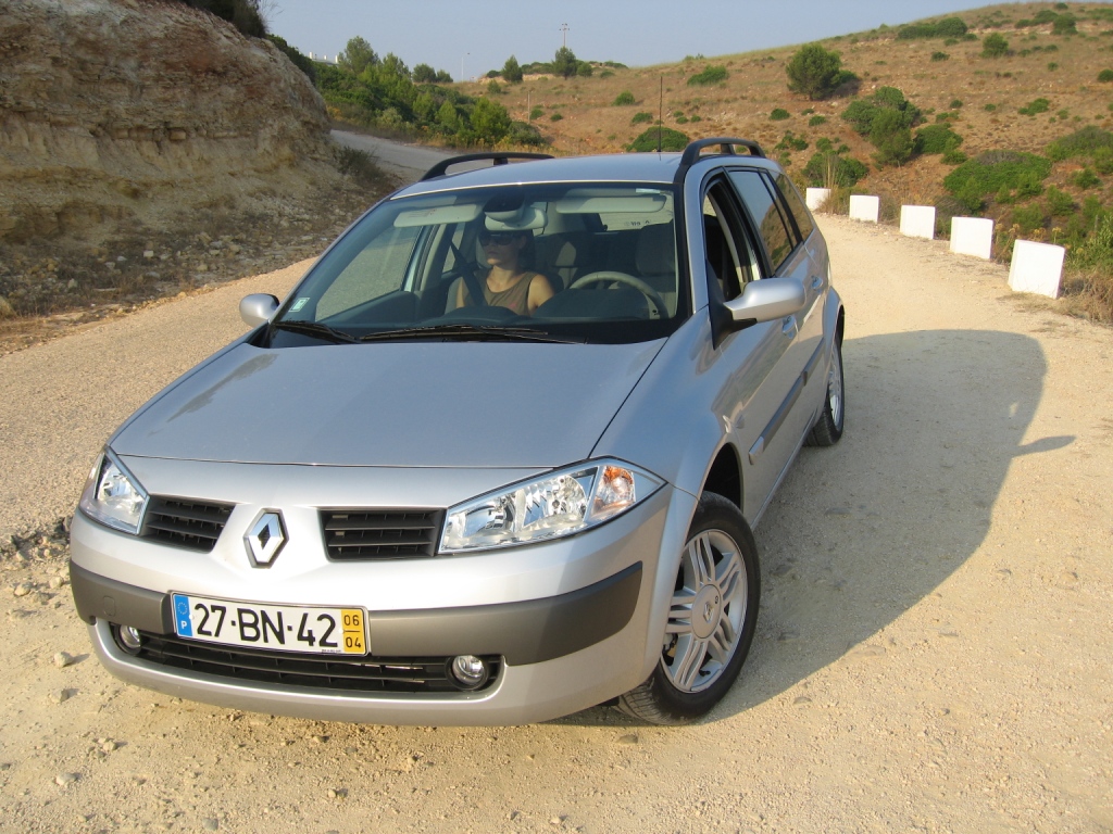 the small car is parked on the side of a dirt road