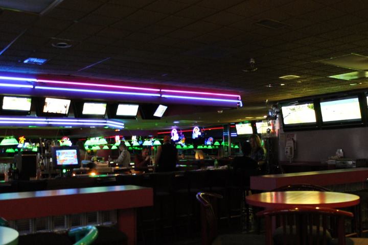 people sit at bar with large televisions behind them
