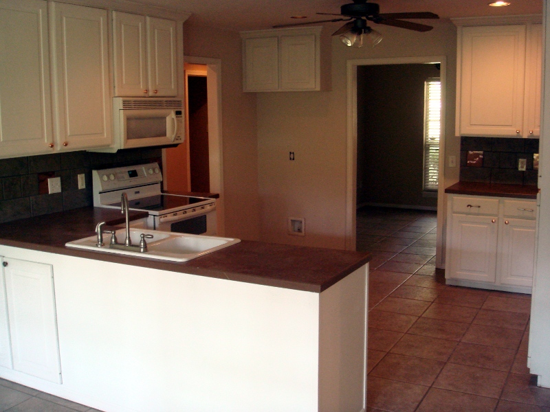 a kitchen with white cabinets, counter top and black floor