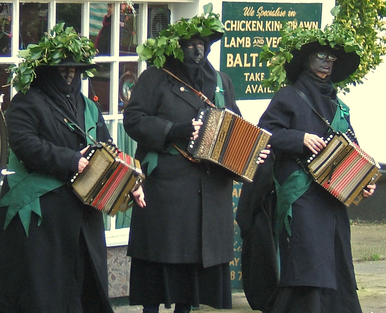 three men wearing black outfits with colorful accordions