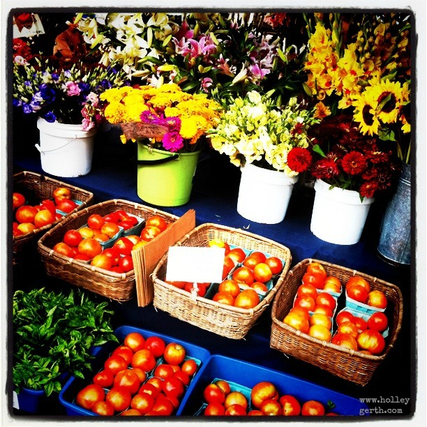 several baskets of fresh tomatoes with flowers in the background