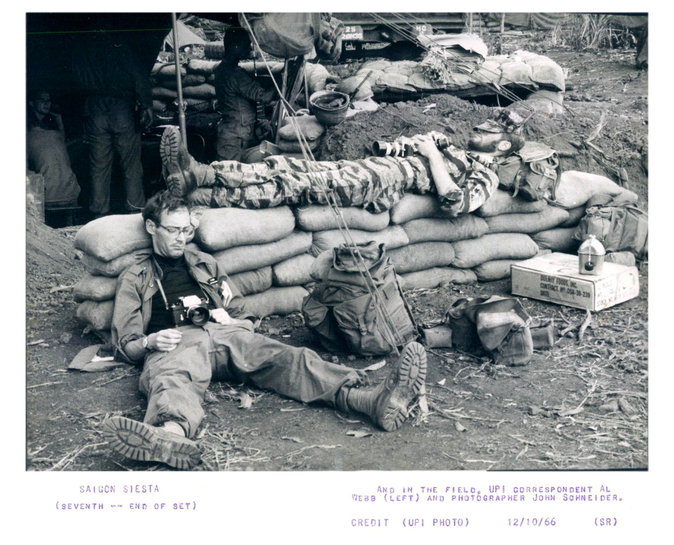 a military couple are sitting on the ground near bags