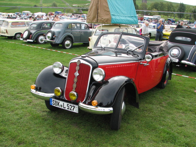 an old model car is parked on the grass