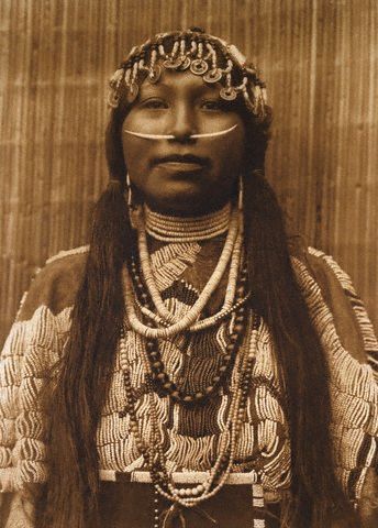 a black - and - white pograph of an indian woman wearing beads