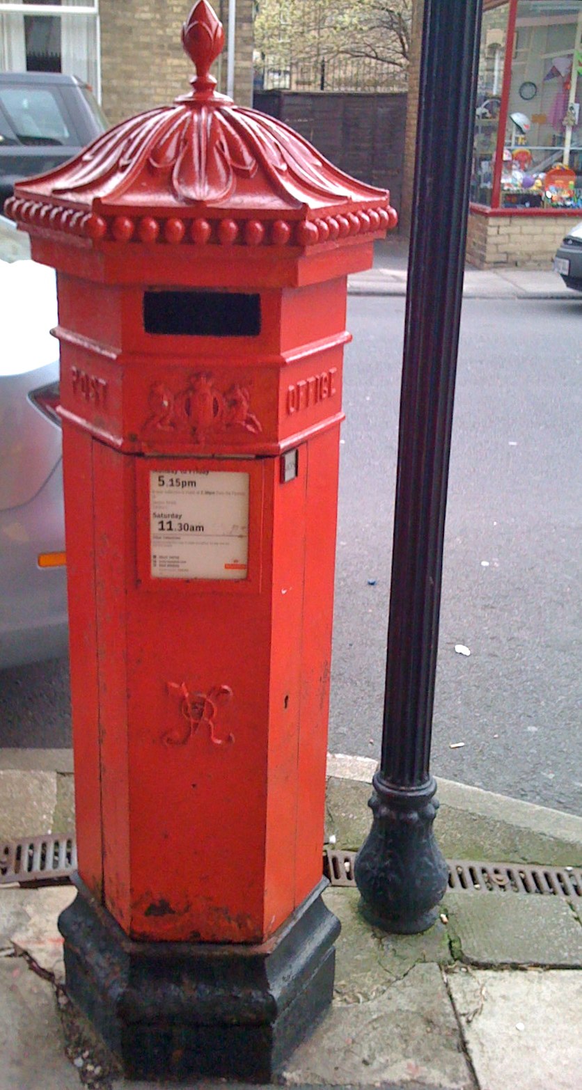 red mail box on sidewalk in front of street with lamp post