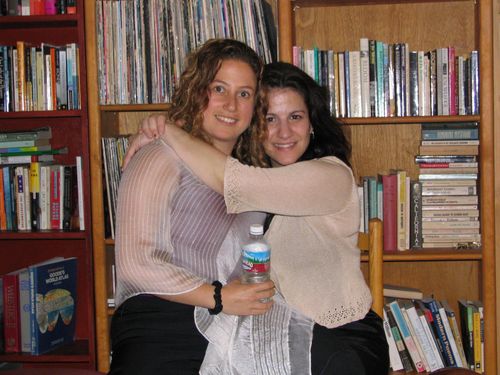 two women hug each other in front of bookshelves