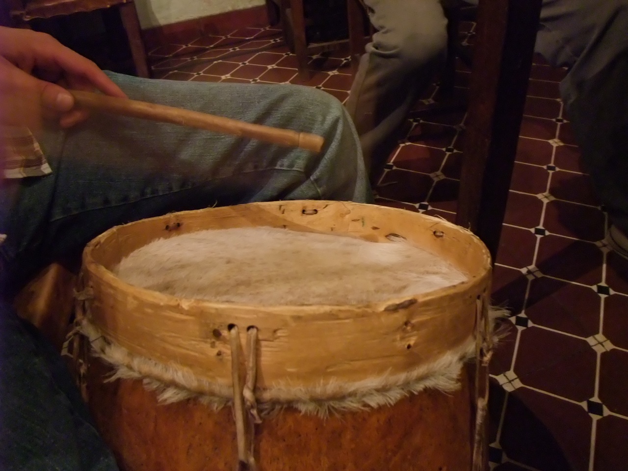 a wooden drum is sitting on the floor with a pair of legs