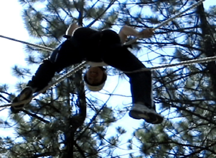 a man flying through the air while riding a zip line