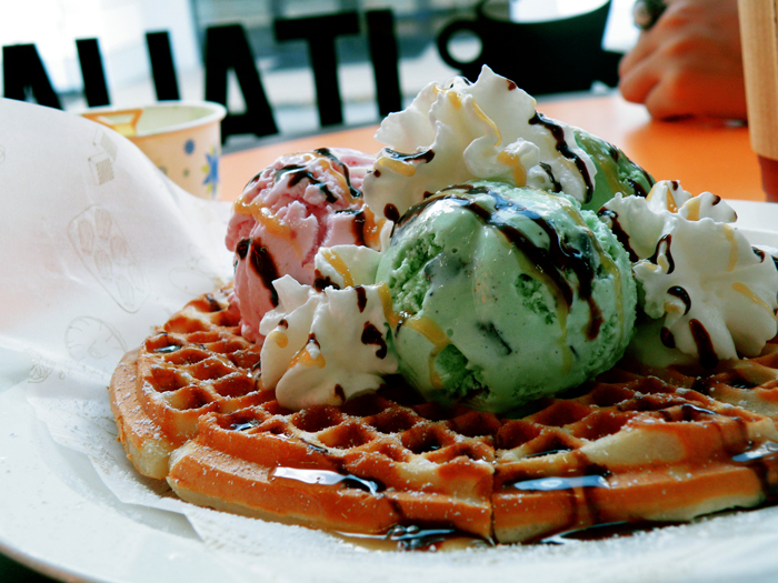 three scoops of ice cream, a waffle and three bananas on a plate