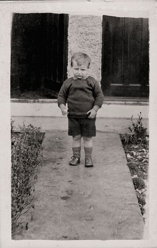 a little boy standing on a sidewalk and staring