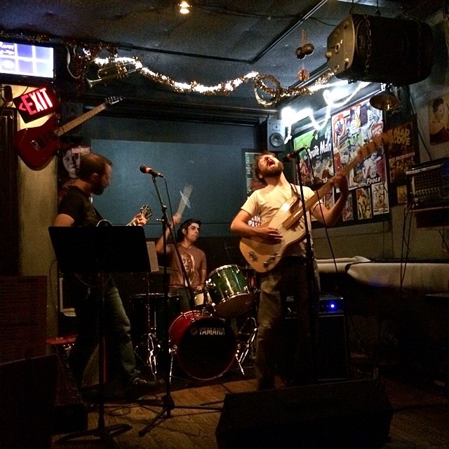 a group of men playing guitars in a room with lights