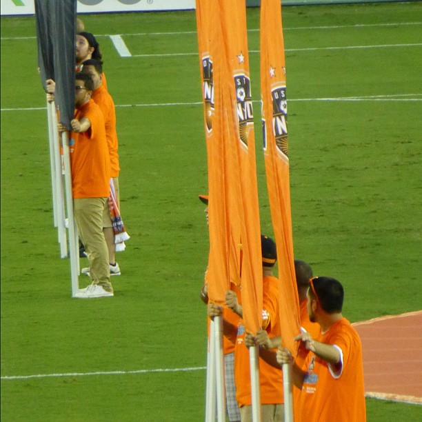 some people in orange shirts standing near some poles