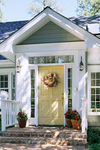 the front of a small home with white siding and flowers