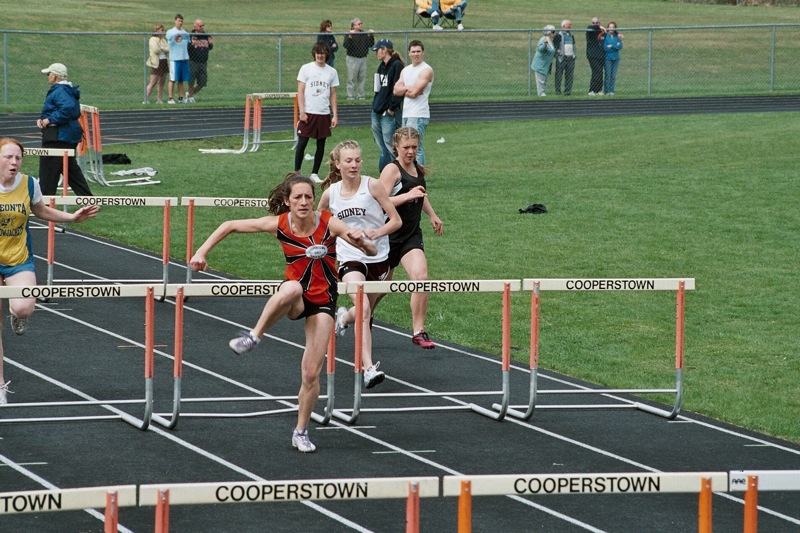 three female competitors are competing in the hurdles