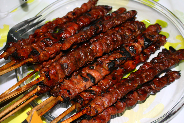 many skewers of meat are stacked on plates
