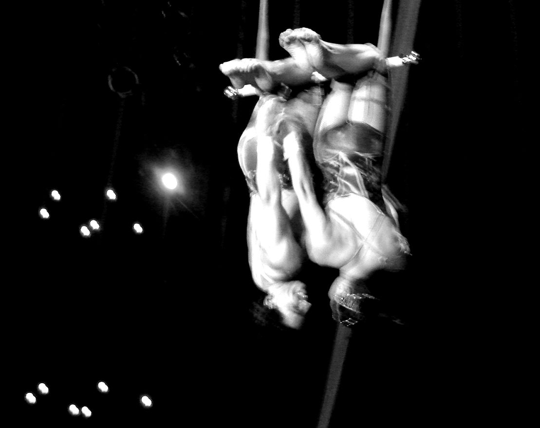 two men are swinging on rope at a circus