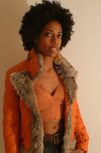 a woman in an orange jacket has a fake fur collar