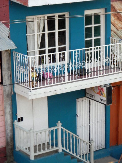 two story house with white balconies and blue door