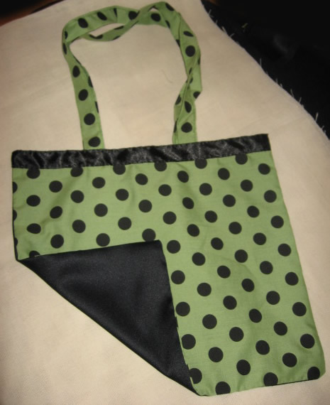 a green polka dot bag is laying on a white tablecloth