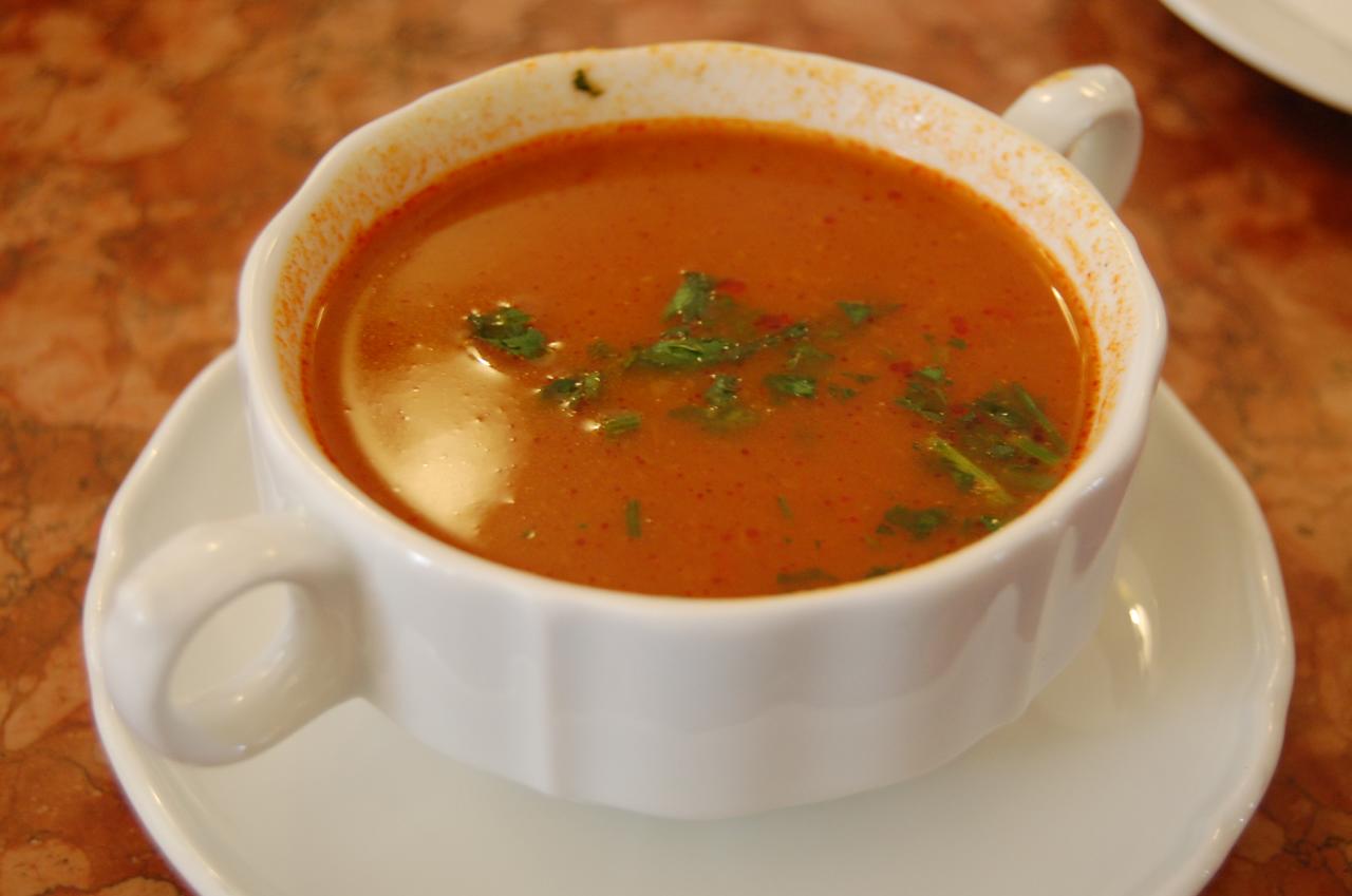 a white plate with a white bowl and some soup on it