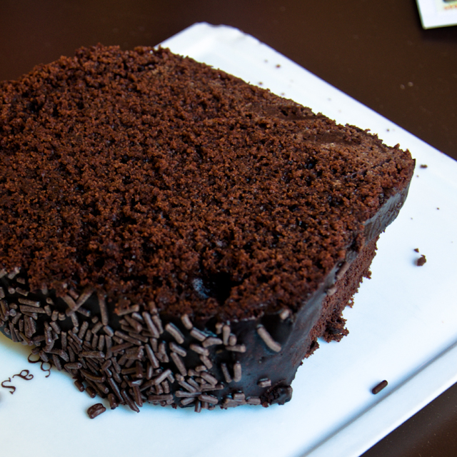 a chocolate cake with chocolate sprinkles sitting on a plate
