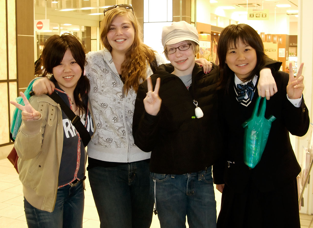 a group of girls giving the peace sign while standing next to each other