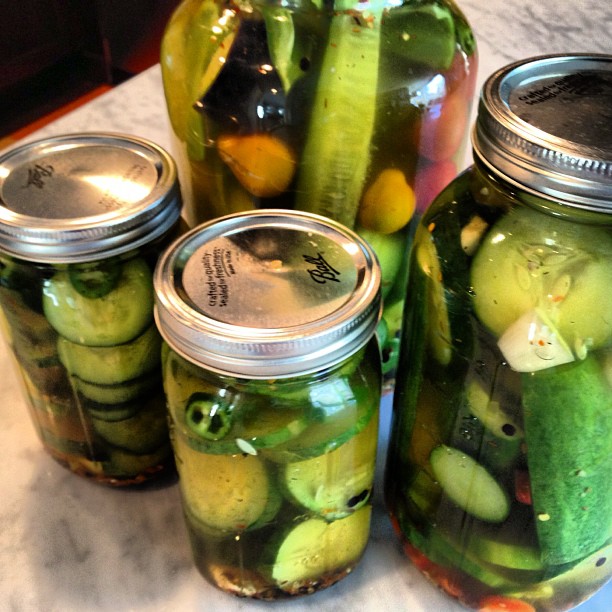 there are three jars full of pickles on the table
