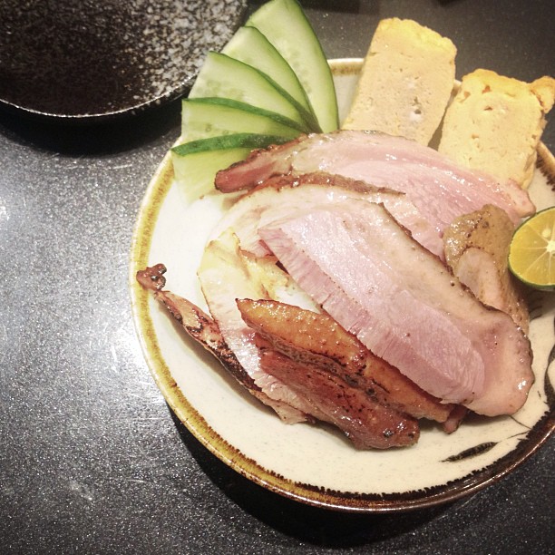 a plate containing a ham and two slices of cucumber