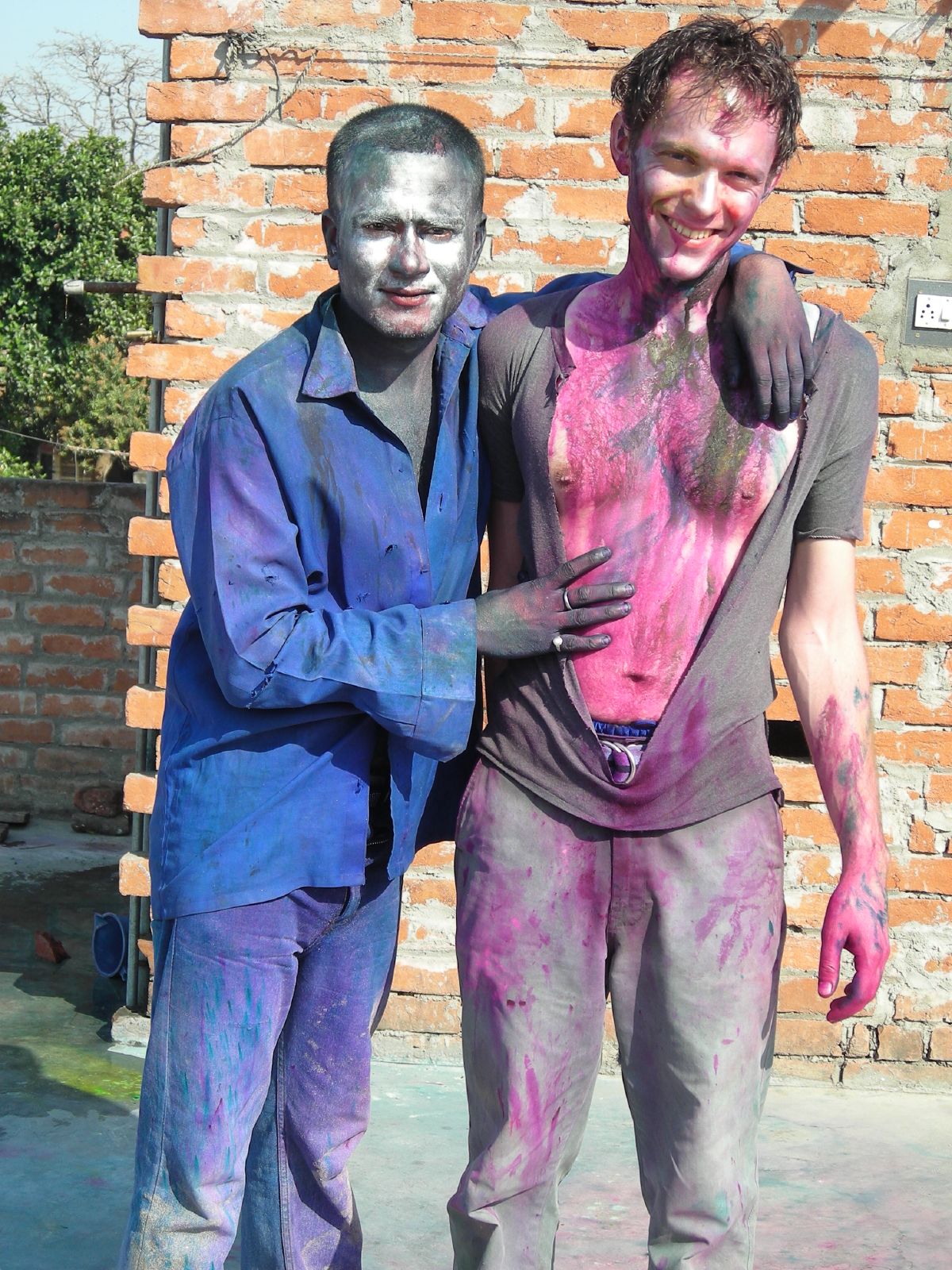 two guys painted in colorful, unique clothes and holding hands