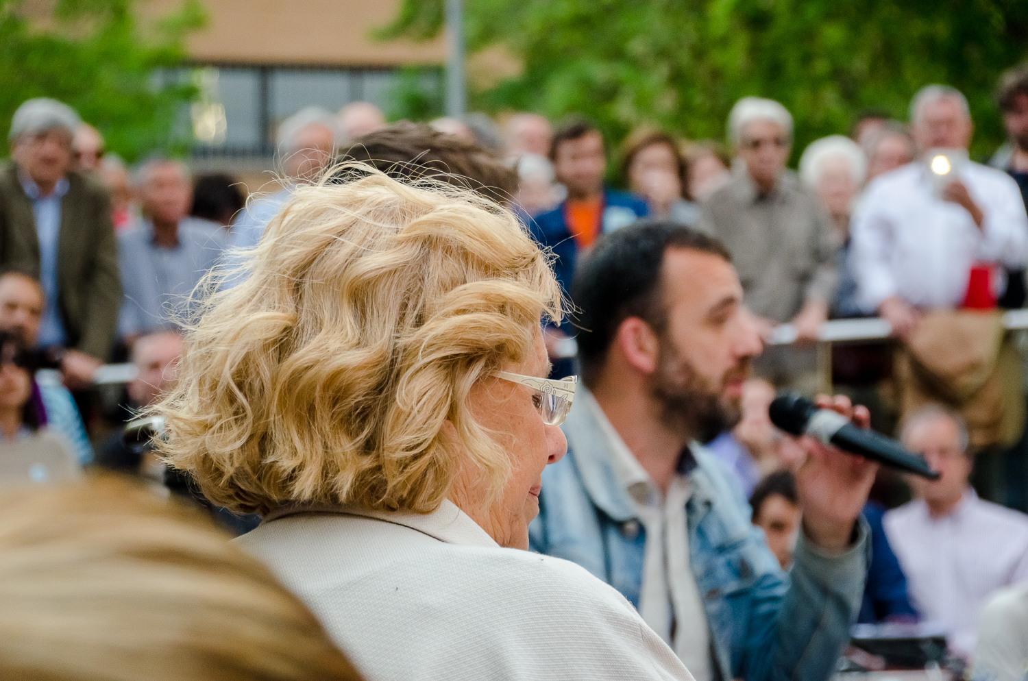 a woman with blonde hair and glasses speaks into a microphone