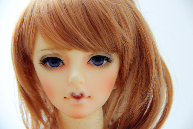 a girl doll head has big blue eyes and orange hair