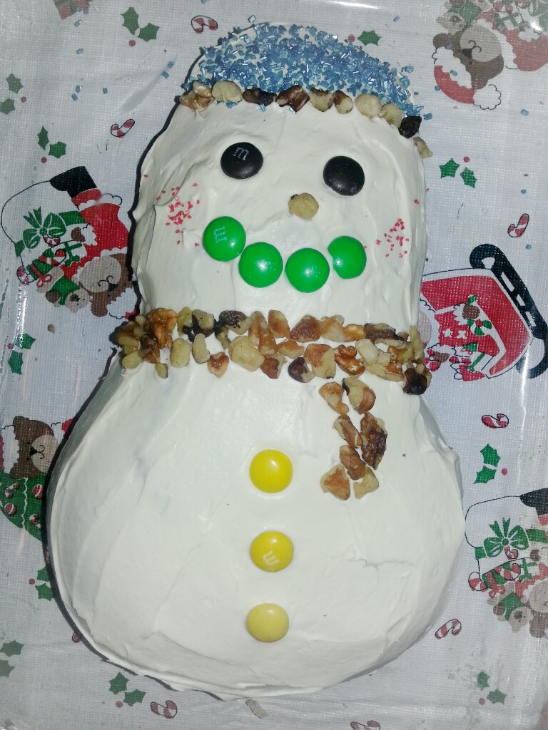 a white frosted snowman has eyes and is wearing a hat