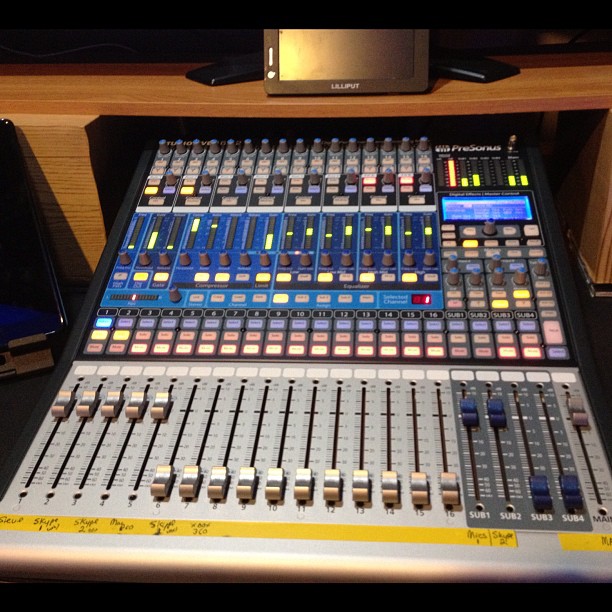 a sound mixing console on a counter next to a monitor