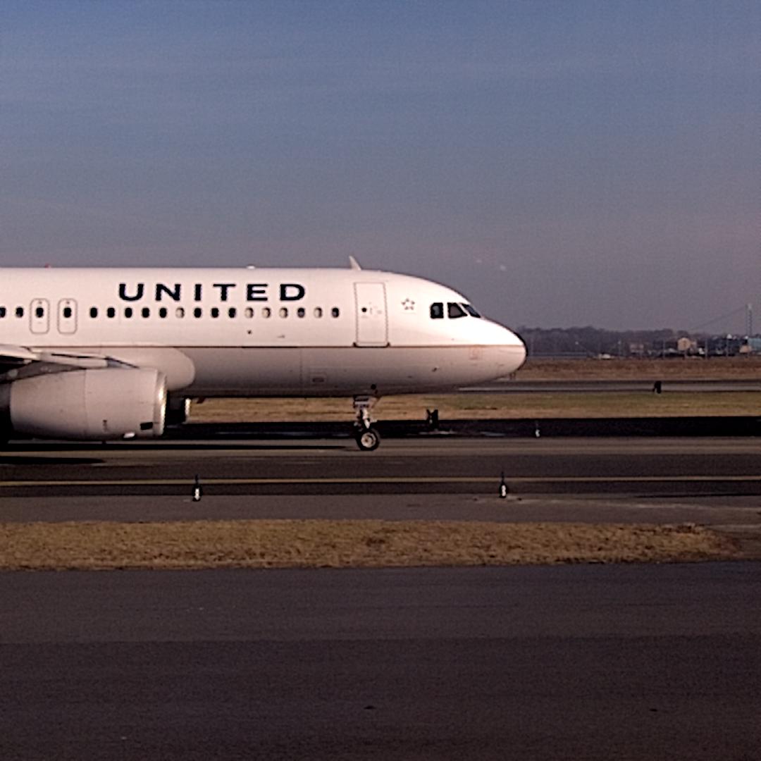 a white united airplane sits on an airport runway