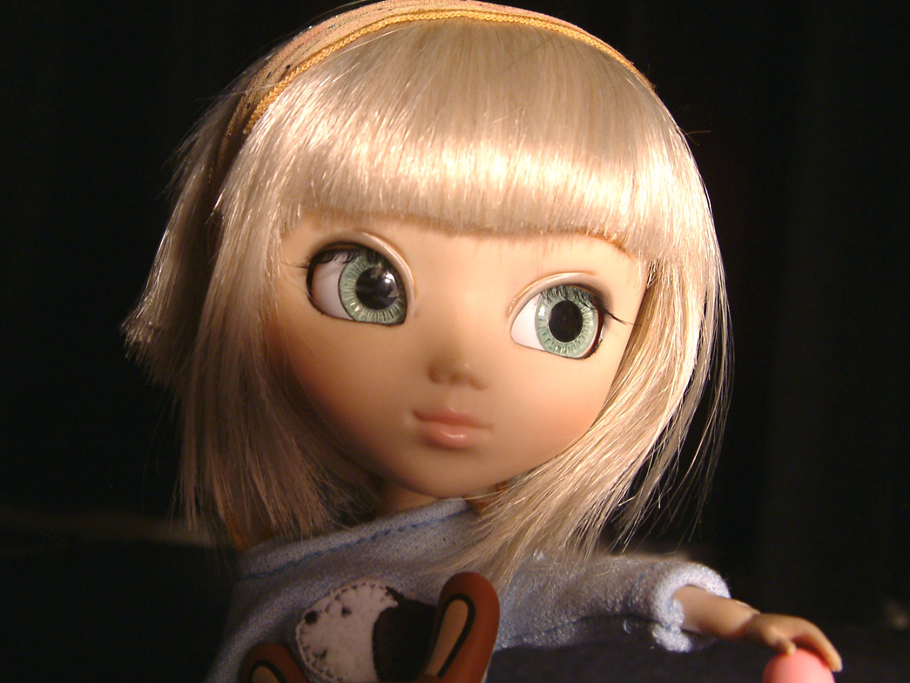 a little doll with blonde hair wearing white sweater
