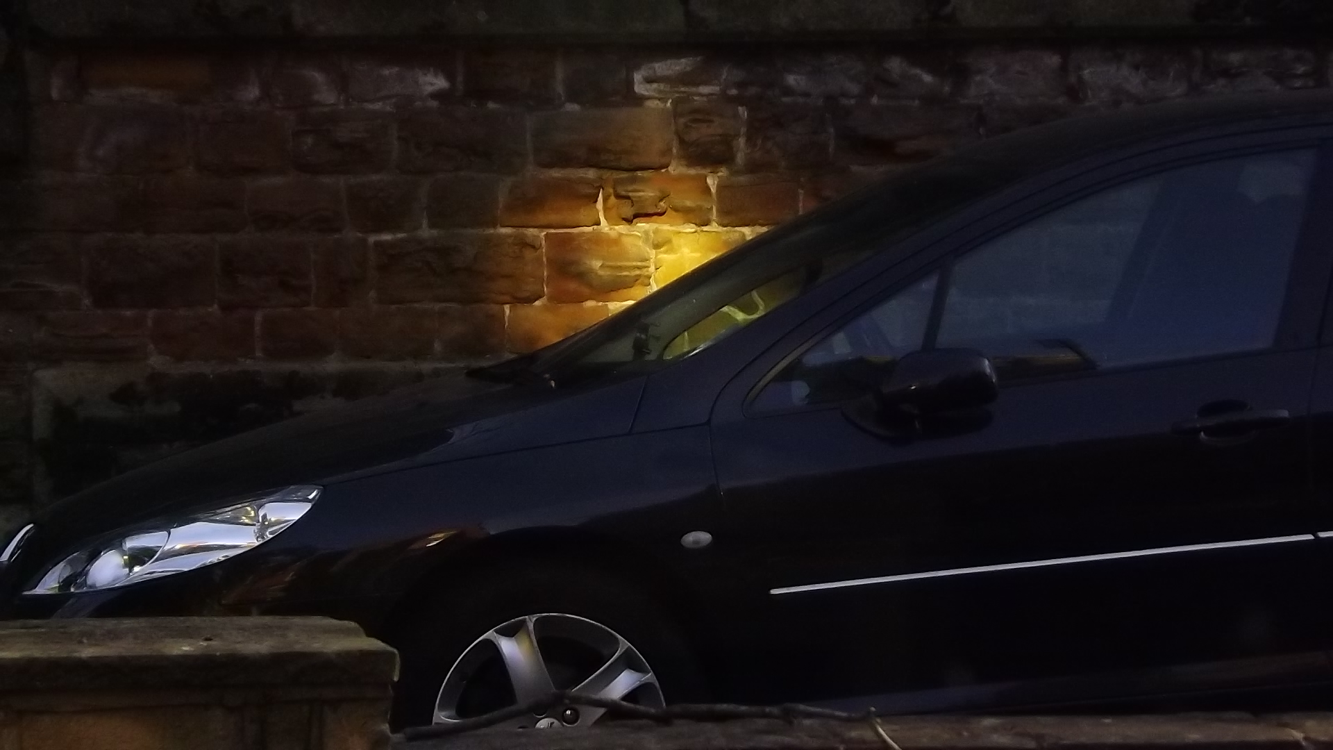 a small dark car parked near a brick building