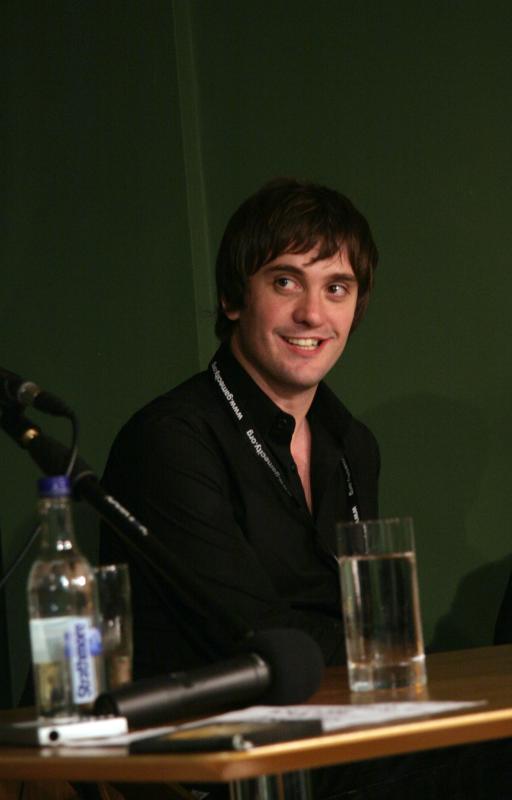 a man wearing black is sitting behind a microphone