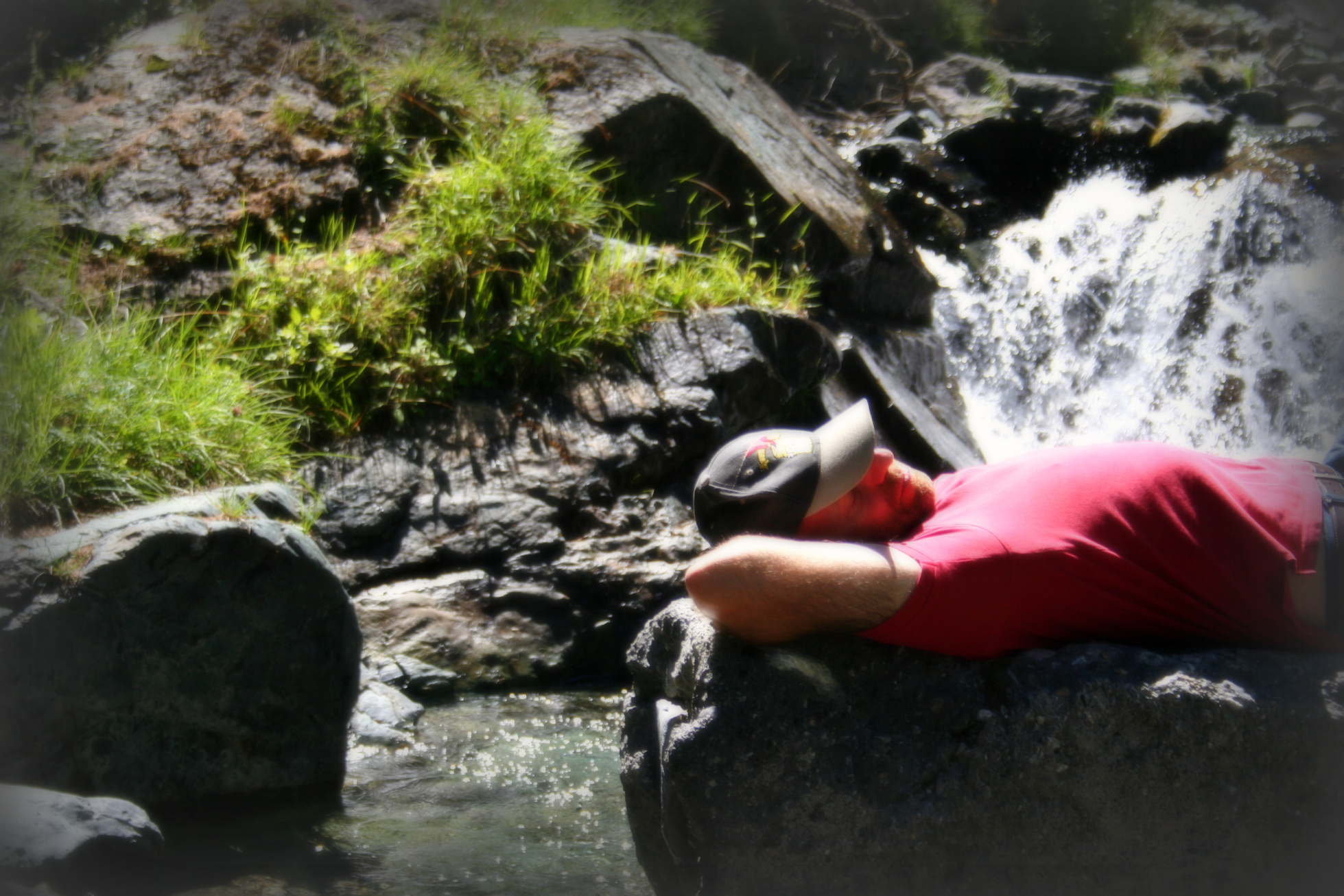 a man resting on the rocks near a water fall