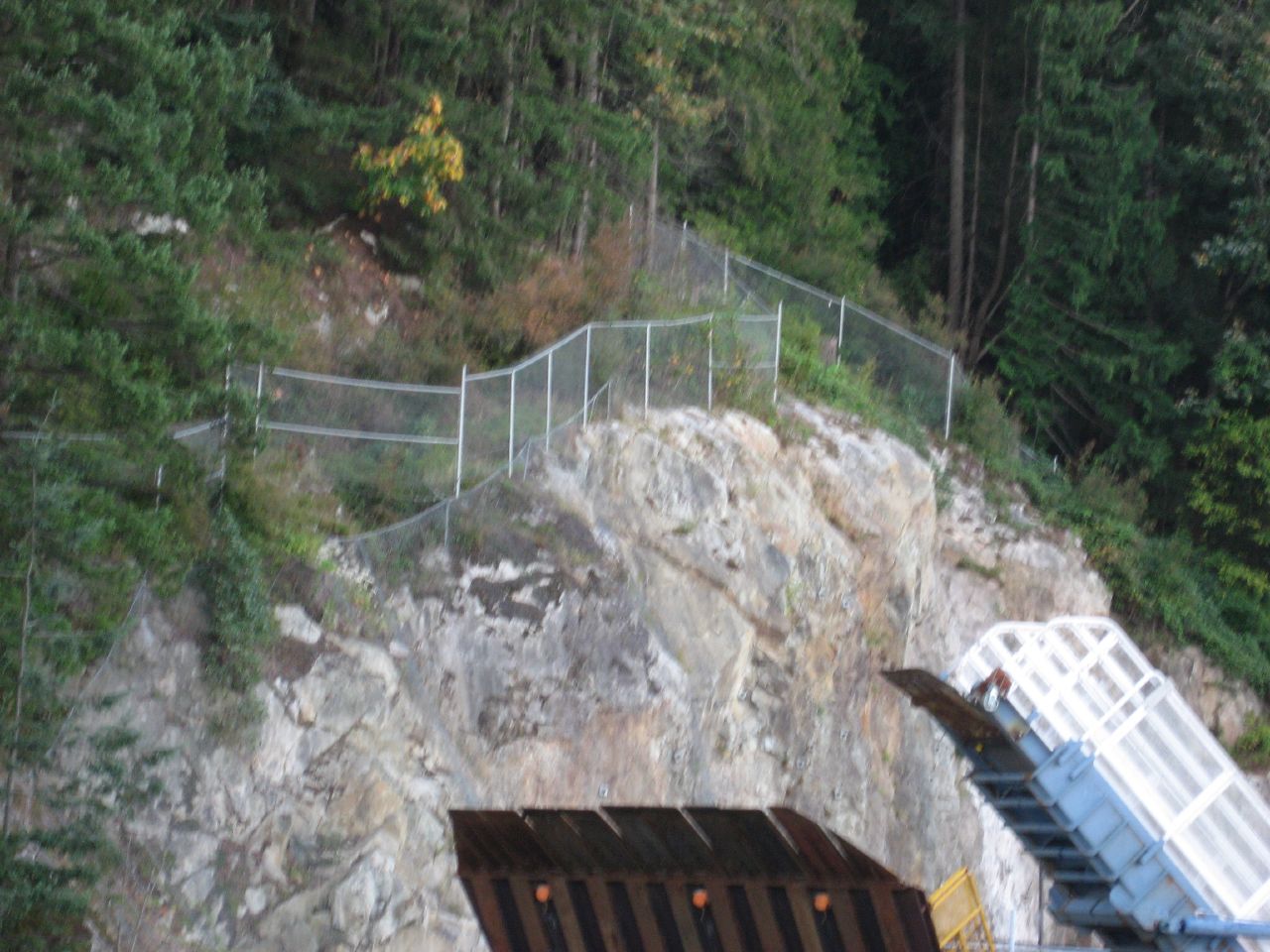 a man walking up the side of a cliff next to a white metal structure