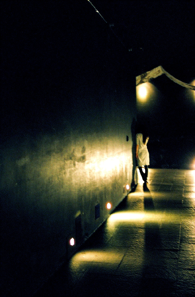 a man standing on a brick sidewalk near some light