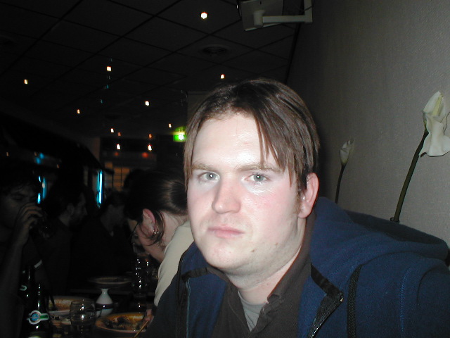man at a dining table in a restaurant looking in to the camera