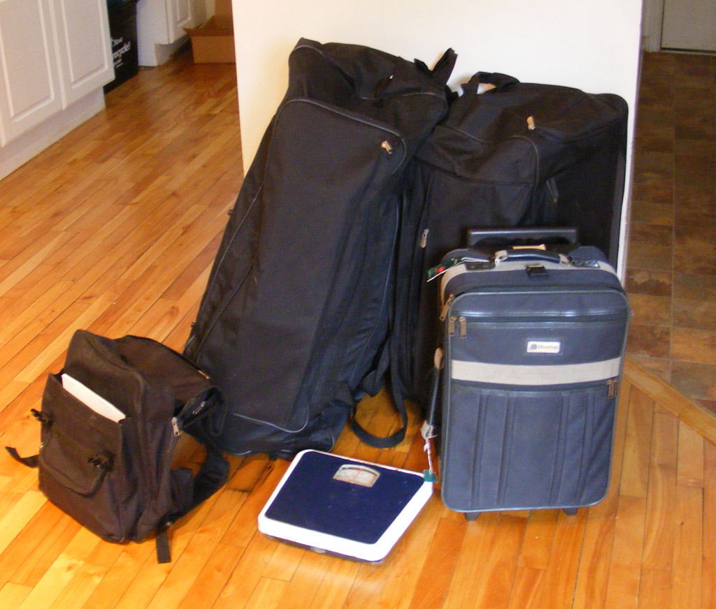 several suitcases on the ground near a scale
