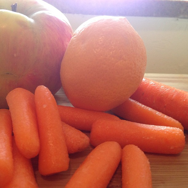 a pile of carrots sitting next to an orange