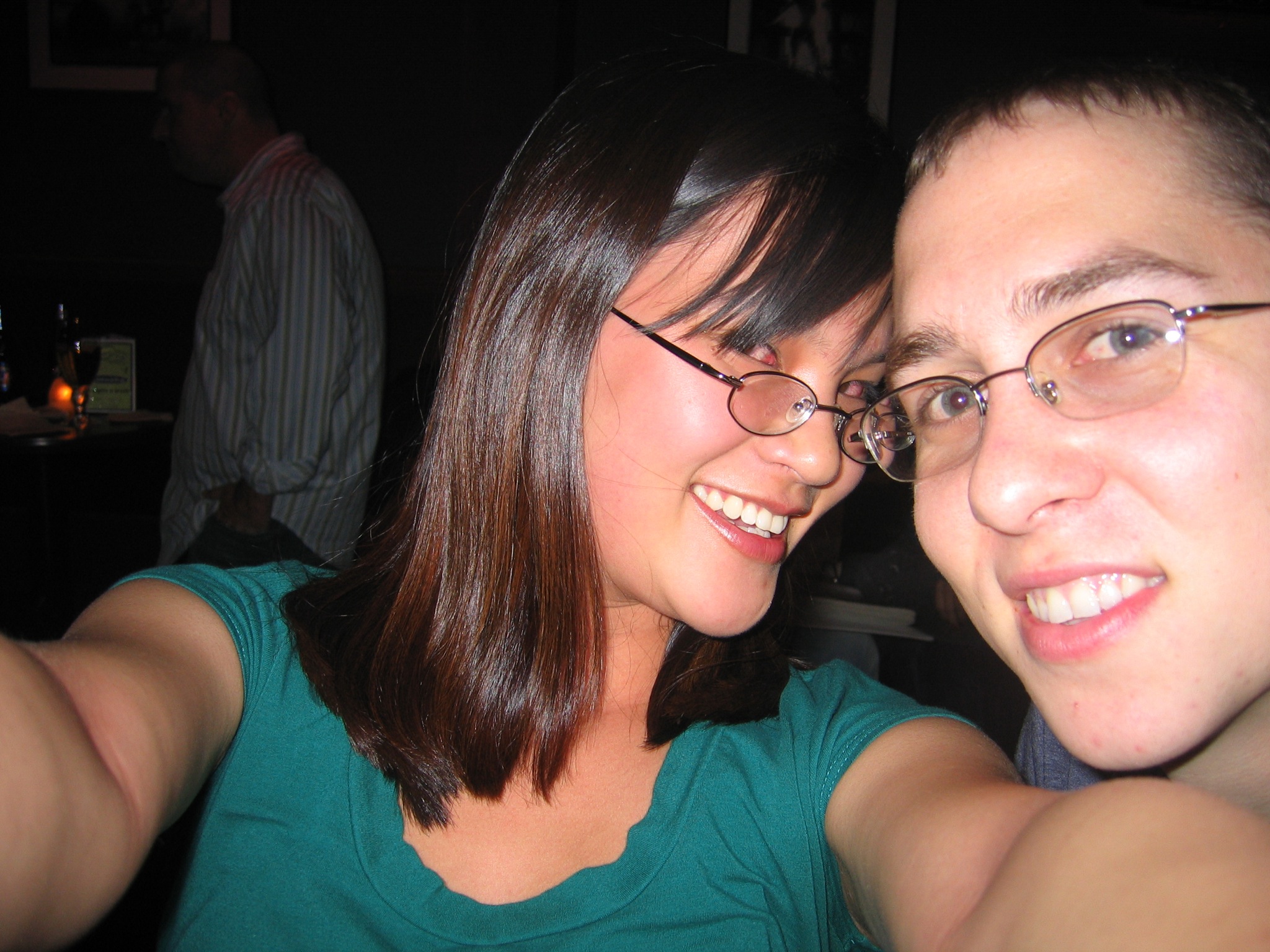 a young couple smiling into the camera, both wearing eye glasses