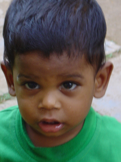 a boy is looking at the camera while wearing a green shirt