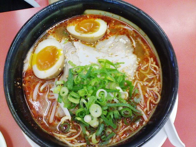 an asian ramen bowl with boiled egg, meat and broth