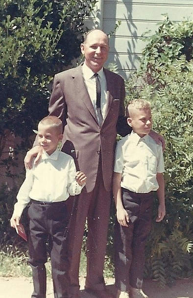 a man in a suit standing with two children